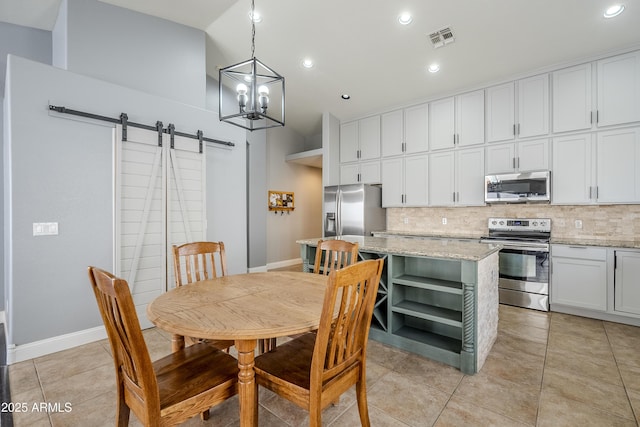 tiled dining room featuring a barn door and a chandelier