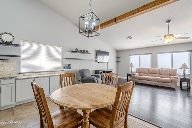 tiled dining area with vaulted ceiling with beams and ceiling fan with notable chandelier