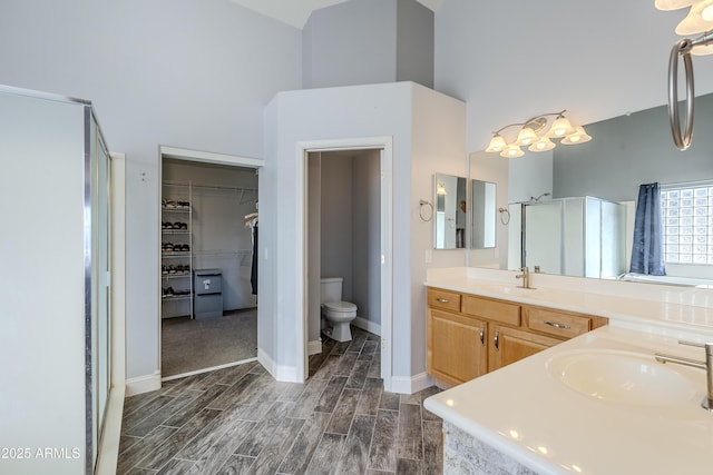 bathroom with vanity, a towering ceiling, a shower with door, and toilet