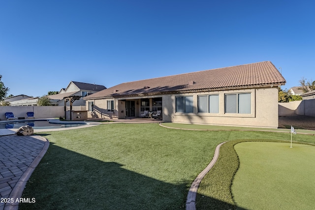 rear view of property with a fenced in pool, a lawn, and a patio