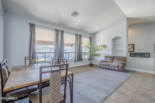 tiled dining area featuring vaulted ceiling and built in features