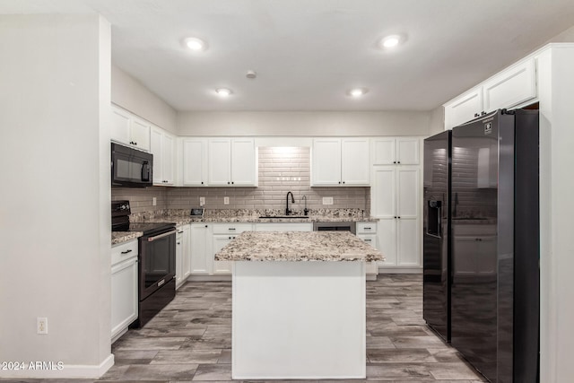 kitchen with light stone countertops, sink, black appliances, light hardwood / wood-style floors, and a kitchen island