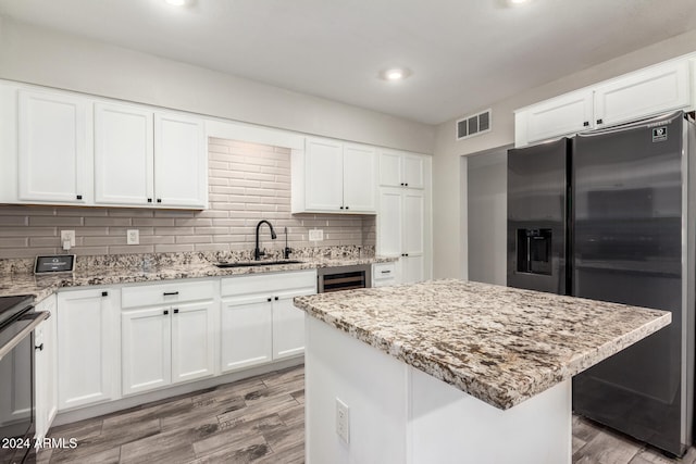 kitchen featuring white cabinets, a kitchen island, wood-type flooring, and appliances with stainless steel finishes