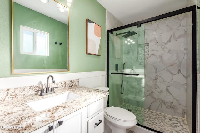 bathroom with a shower with door, vanity, and toilet