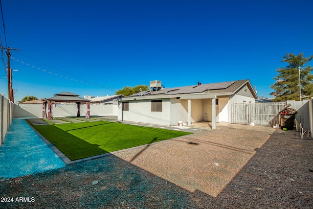 rear view of house with a gazebo, solar panels, a patio area, and a yard