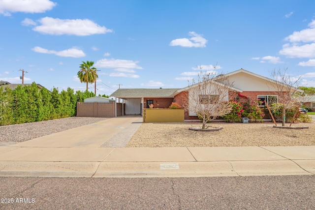 ranch-style house with brick siding, concrete driveway, a carport, and fence