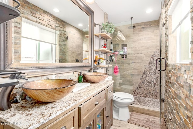 full bath with toilet, tile walls, a stall shower, and vanity