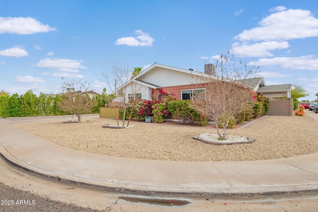 ranch-style home with a chimney and fence