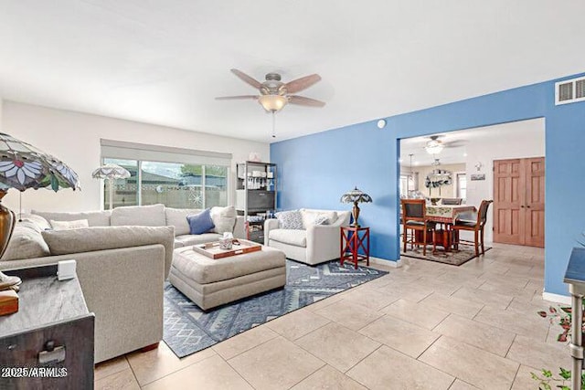 living area featuring light tile patterned floors, visible vents, baseboards, and ceiling fan