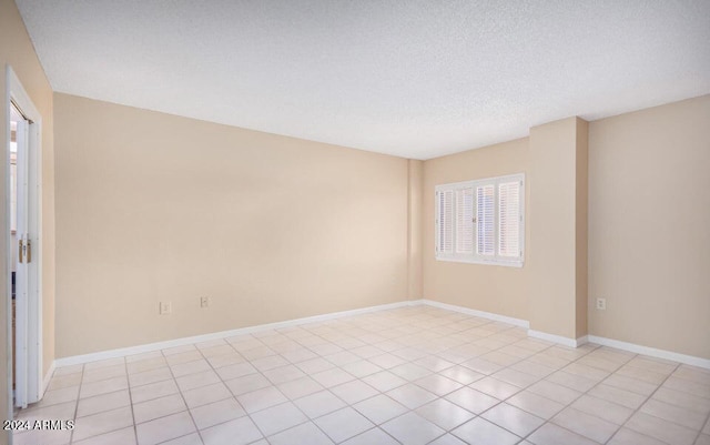 unfurnished room with a textured ceiling and light tile patterned floors