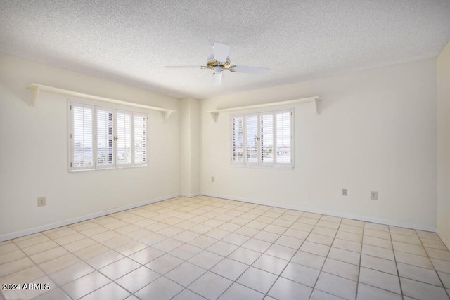 empty room with ceiling fan, a textured ceiling, and light tile patterned floors