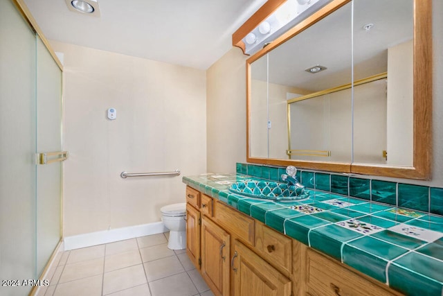 bathroom featuring a shower with door, toilet, vanity, decorative backsplash, and tile patterned flooring