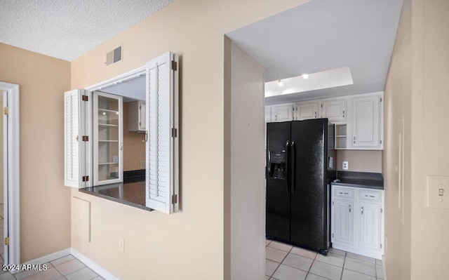 kitchen with black refrigerator with ice dispenser, white cabinets, a textured ceiling, and light tile patterned floors