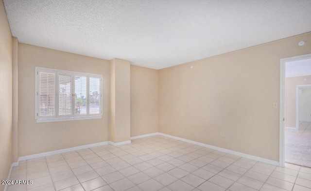 empty room featuring a textured ceiling and light tile patterned floors