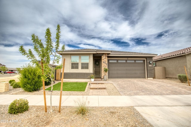 view of front of house featuring decorative driveway, an attached garage, and stucco siding