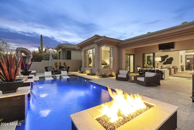 pool at dusk with pool water feature, a fire pit, and a patio area