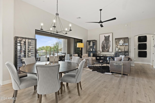 dining area with light hardwood / wood-style floors and ceiling fan with notable chandelier