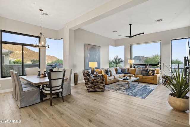 living room featuring ceiling fan with notable chandelier, light hardwood / wood-style flooring, and a mountain view