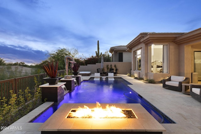 pool at dusk featuring an outdoor fire pit, pool water feature, and a patio