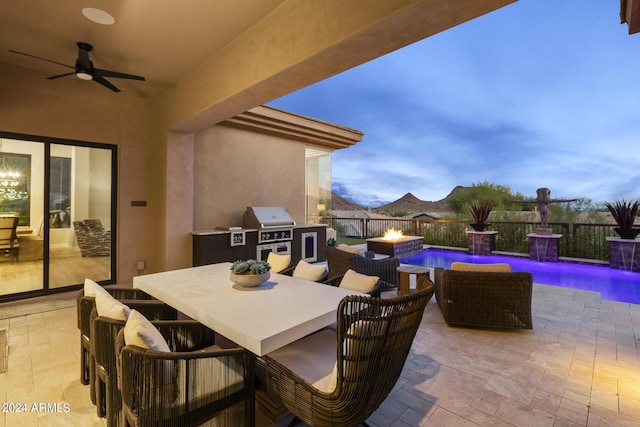 patio terrace at dusk featuring grilling area, a fenced in pool, area for grilling, ceiling fan, and pool water feature