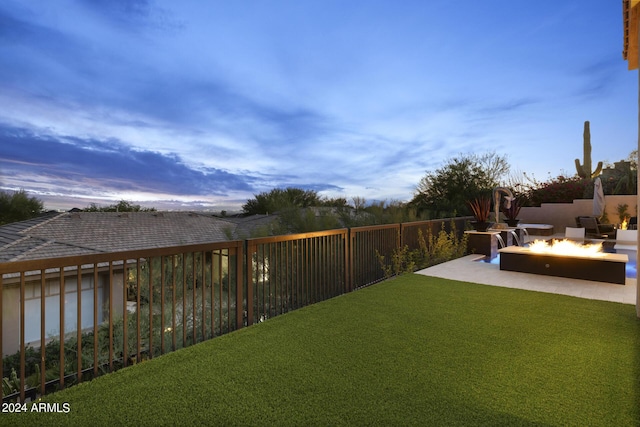 yard at dusk featuring a patio area and a fire pit