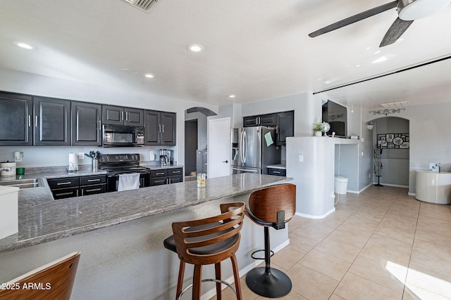 13547 W Peck Dr, Litchfield Park, AZ 85340 - kitchen with arched walkways, light tile patterned flooring, light stone countertops, a peninsula, and black appliances