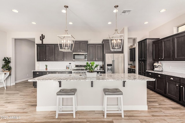 2065 N Red Clf, Mesa, AZ 85207 - kitchen with appliances with stainless steel finishes, a chandelier, backsplash, recessed lighting, and an island with sink