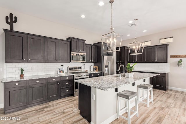 2065 N Red Clf, Mesa, AZ 85207 - kitchen featuring stainless steel appliances, a chandelier, tasteful backsplash, a breakfast bar area, and light wood-type flooring