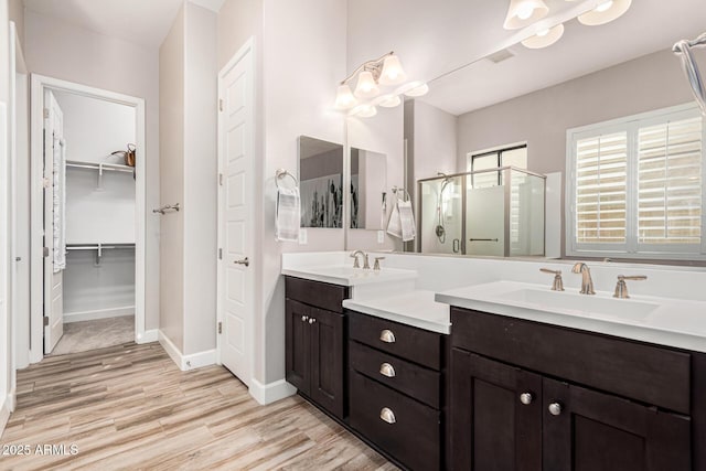 2065 N Red Clf, Mesa, AZ 85207 - bathroom featuring a shower stall, double vanity, wood finished floors, a walk in closet, and baseboards
