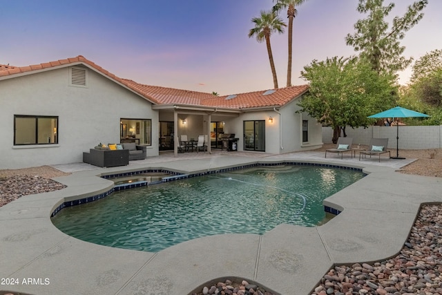 pool at dusk with a patio, an in ground hot tub, and outdoor lounge area