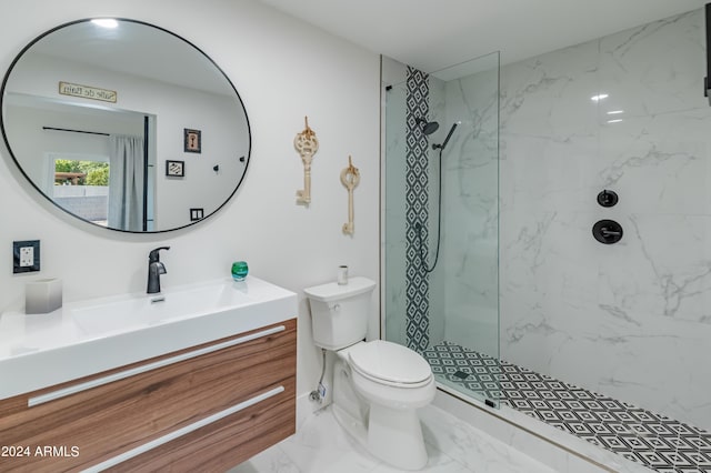 bathroom with toilet, tiled shower, and vanity