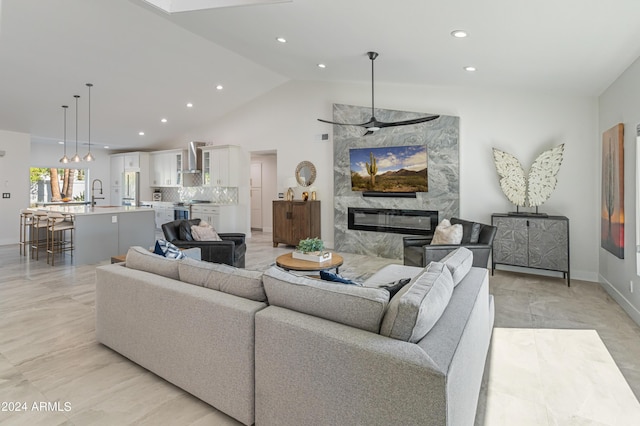 living room with a high end fireplace, high vaulted ceiling, and sink