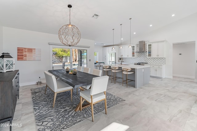 dining area featuring an inviting chandelier, vaulted ceiling, and sink