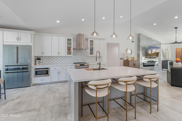 kitchen featuring stainless steel appliances, white cabinets, backsplash, and wall chimney exhaust hood