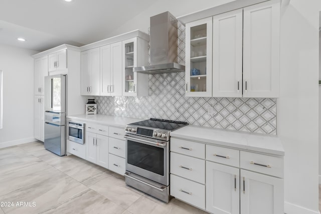 kitchen with decorative backsplash, wall chimney range hood, white cabinetry, and appliances with stainless steel finishes