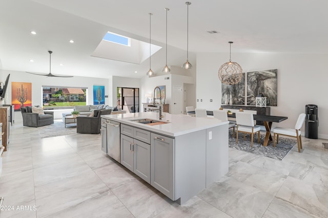 kitchen featuring ceiling fan, hanging light fixtures, lofted ceiling, and a center island with sink