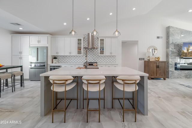 kitchen featuring stainless steel refrigerator, lofted ceiling, wall chimney exhaust hood, white cabinets, and backsplash