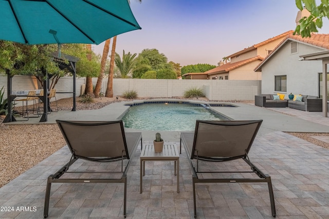 pool at dusk featuring a patio area and an outdoor living space