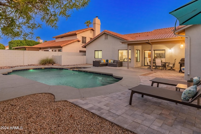 pool at dusk with a grill, an outdoor living space, and a patio area