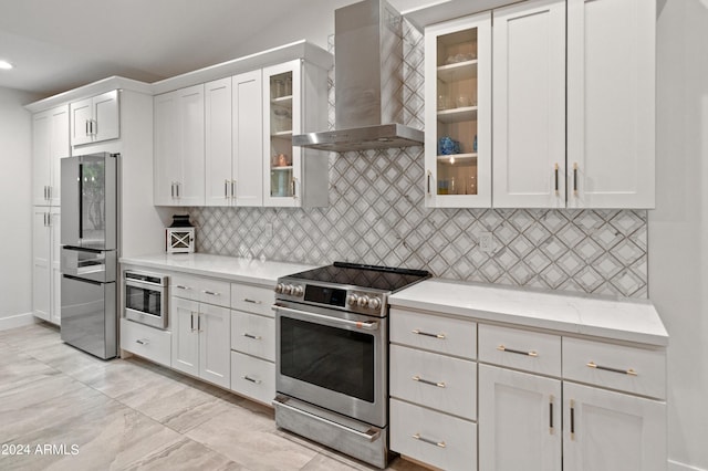 kitchen with stainless steel appliances, light stone countertops, wall chimney range hood, and white cabinetry