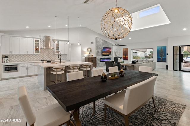 dining space featuring sink, high vaulted ceiling, an inviting chandelier, and a fireplace