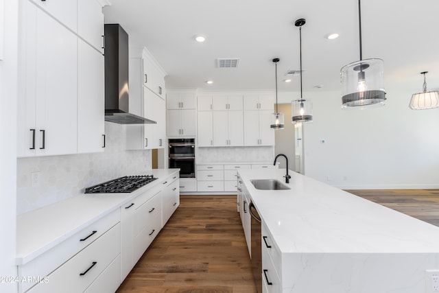 kitchen featuring visible vents, stainless steel appliances, a sink, a large island, and wall chimney exhaust hood