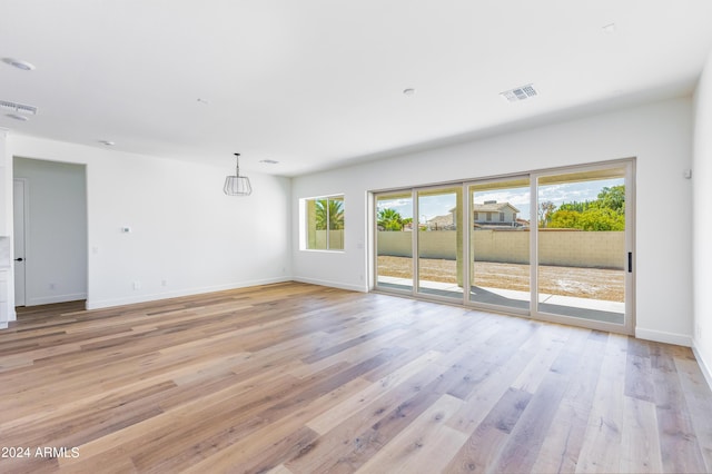 unfurnished room featuring light wood-type flooring, visible vents, and baseboards