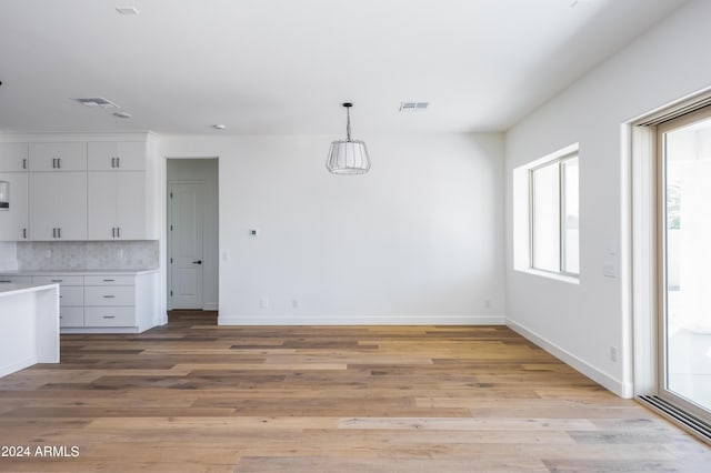 unfurnished dining area featuring light wood finished floors, visible vents, and baseboards