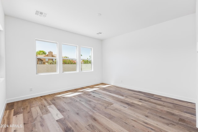 unfurnished room with visible vents, baseboards, and wood finished floors