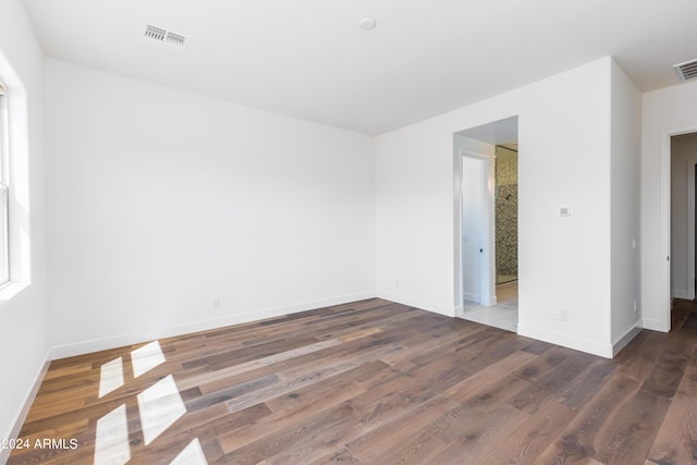 spare room featuring visible vents, baseboards, and wood finished floors