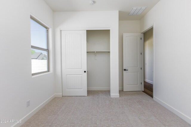 unfurnished bedroom with a closet and light colored carpet