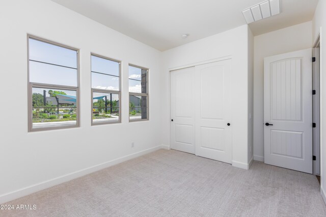 unfurnished bedroom featuring a closet and light colored carpet