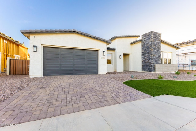 view of front facade with decorative driveway, fence, a garage, and stucco siding