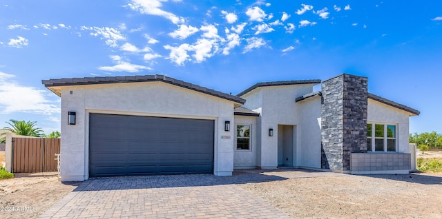 view of front of property with stucco siding, an attached garage, decorative driveway, and fence